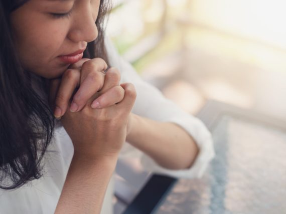 Woman with hands folded in prayer